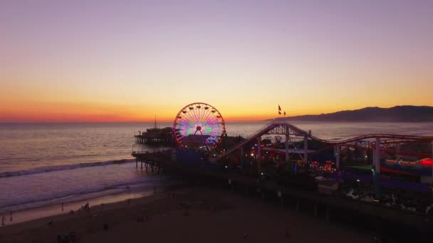 Zdjęcie lotnicze molo Santa Monica i diabelski młyn na plaży o zachodzie słońca — Wideo stockowe