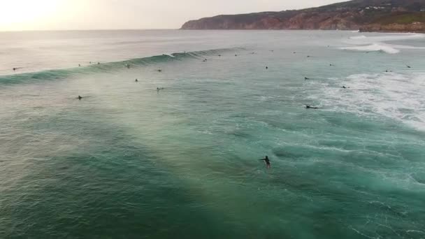 Aufnahme aus der Höhe des Meeres mit Surfern, die aufs Meer hinaus schwimmen und auf Wellen reiten — Stockvideo