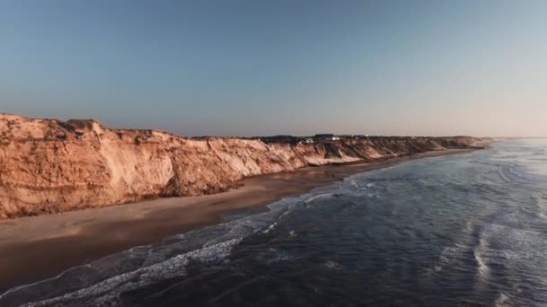Volez au-dessus de la plage au bord de la mer alors que la caméra se dirige vers les maisons — Video