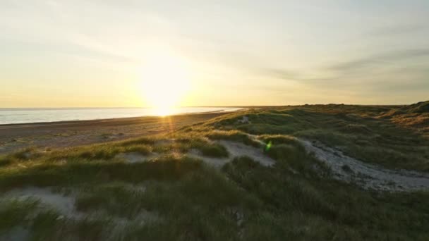 Orange himmel, soluppgång bländning och den långa sträckan av gräsbevuxna länder och stranden vid stranden — Stockvideo