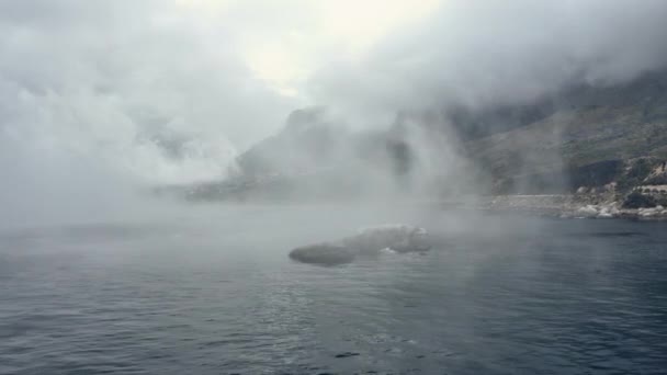 Tiro de rastreo aéreo cerca de la costa del océano y las montañas detrás de la niebla — Vídeos de Stock