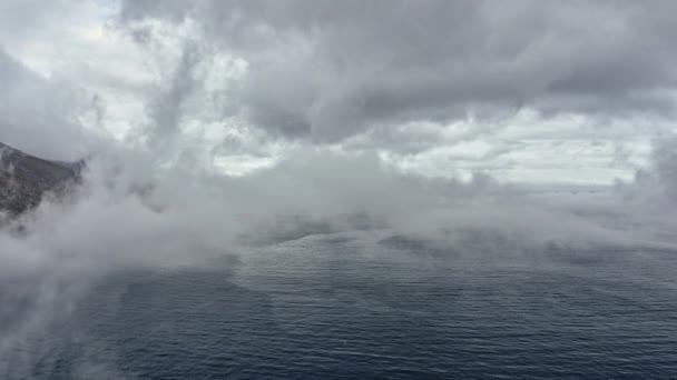 Tiro de seguimiento aéreo hacia atrás de las aguas del océano y la niebla que cubre el marco — Vídeos de Stock