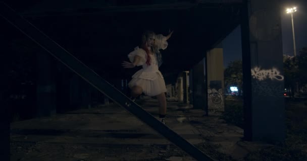 Mulher de vestido branco e maquiagem Harleyquin balanceamento em trilhos de metal — Vídeo de Stock
