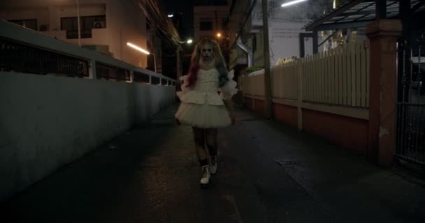 Gruseliger Clown im weißen Kleid spaziert durch die Gasse — Stockvideo