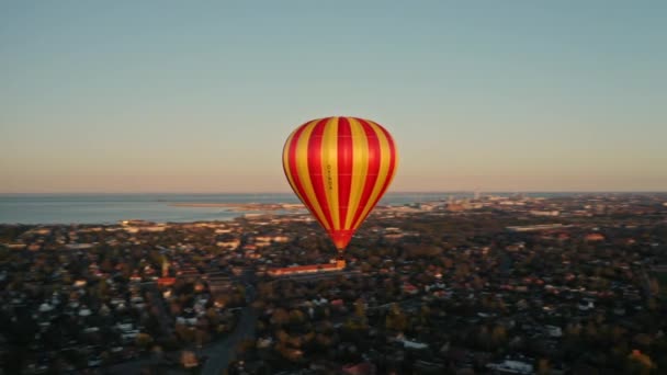 Globo de aire caliente de rayas amarillas y naranjas flotando sobre las calles de la ciudad — Vídeo de stock