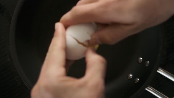 Slow motion shot of hands Cracking an Egg on Black Pan — Stock video