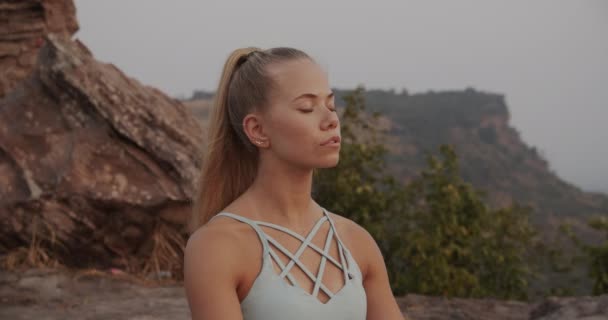 Tiro de medio cuerpo de mujer con los ojos cerrados meditando en la cima de la montaña — Vídeos de Stock