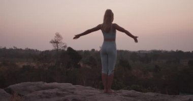 Sarışın kadın Rock 'ın yanında meditasyon yapıyor.