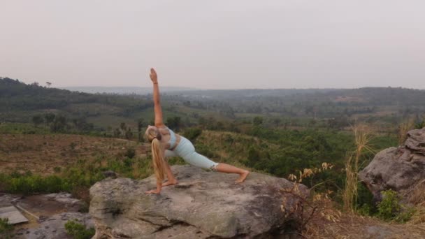 Aerial Shot of Lady in Downward Dog Yoga Pose with a View from the Top of the Mountain — Stock Video