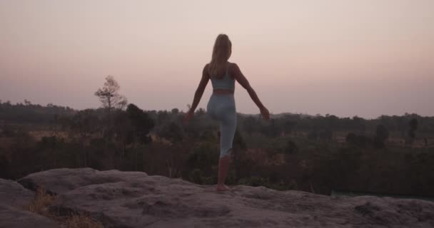 Fit Kobieta modelka stoi na jednej nodze przy skałach robi jogę — Wideo stockowe