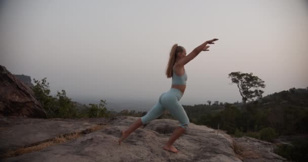 Vrouw doet de Krijger Yoga Pose als ze staat bij de Mountain Rocks — Stockvideo