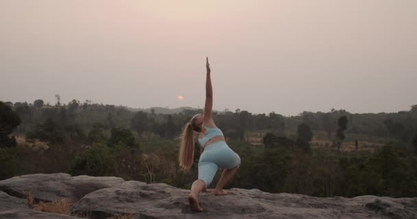 Женщина в восставшем треугольнике Поза йоги на улице у горы — стоковое видео