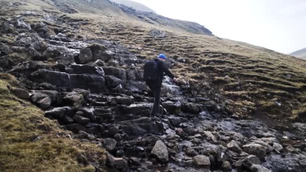 Man Going Across Rocky Stream e Cliff con un cielo luminoso sullo sfondo — Video Stock