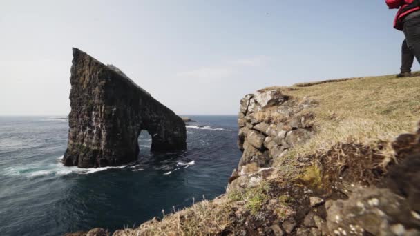 海に囲まれた崖の中をゆっくり歩く男 — ストック動画