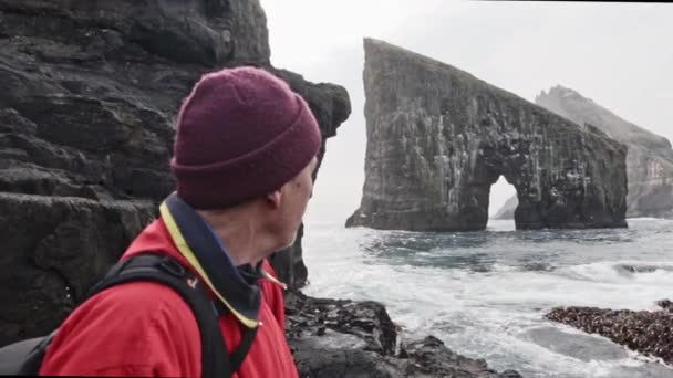 Muž Cestovatel Hledající Sideways a krásný výhled na moře stohy podél Faerských ostrovů — Stock video