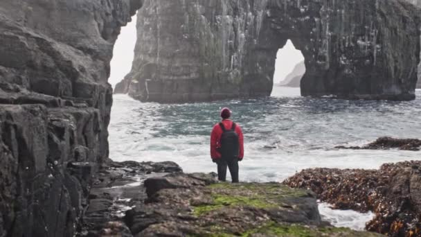 Viaggiatore In piedi ai piedi di una scogliera Ammirando Drangarnir Gates — Video Stock