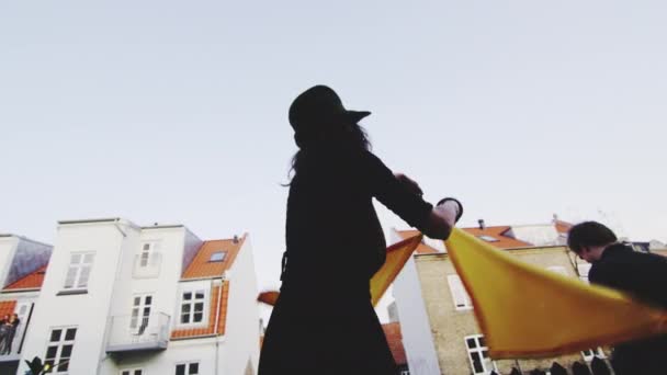 Vacker Skott av en kvinna viftande två gula flaggor under en Street Party — Stockvideo