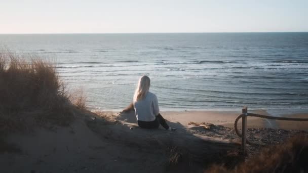 Ung kvinna sitter ensam på stranden — Stockvideo