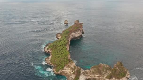 Вид с высоты птичьего полета на скалу, окруженный глубокими голубыми морями в Нуса-Пениде — стоковое видео