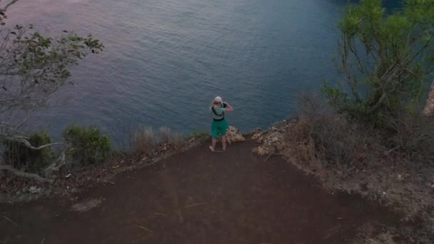 Viajante feminino com uma câmera na mão tirando fotos do topo do penhasco — Vídeo de Stock