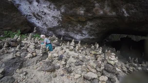 Женщина на коленях у входа в пещеру исследует скалы — стоковое видео