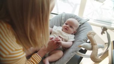 Fedai sandalyesinde otururken annesi tarafından bakılan tatlı bir bebek.
