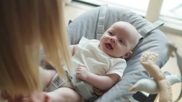 Moderns rörliga babyben med barnet liggande på grå utkastarstol — Stockvideo