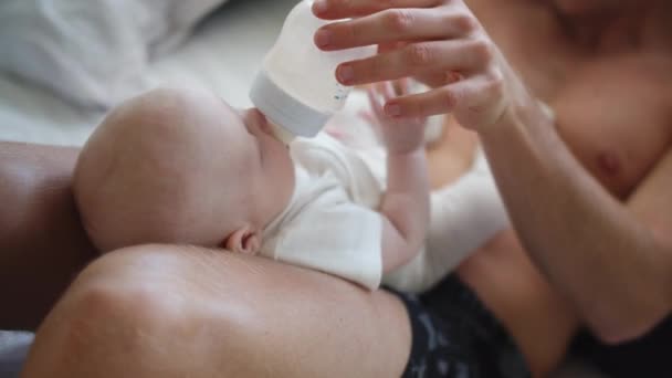 Roztomilé malé dítě kolébka na otcově Lap krmení mléka přes láhev — Stock video