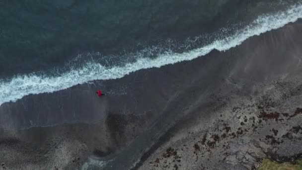 Drone schot van de mens wandelen langs het strand op de Faeröer eilanden — Stockvideo
