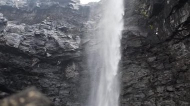 Aşağıda gezinen yürüyüşçüyle Uçurumdan akan su