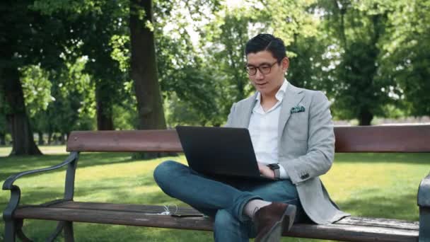 Empresario coreano trabajando en el ordenador portátil en el parque — Vídeos de Stock