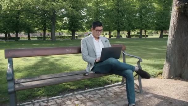 Empresário coreano no laptop no parque — Vídeo de Stock