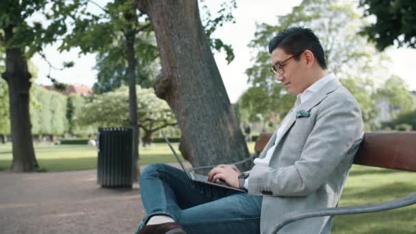 Koreaanse zakenman gebruikt laptop in het park — Stockvideo