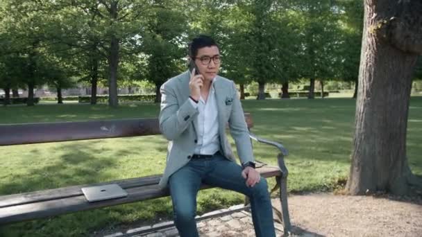 Koreai üzletember telefonál a parkba — Stock videók