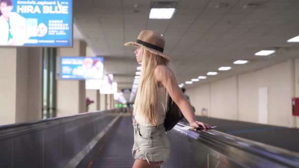 Žena na stojící bok po boku na pohybující se chodníku na letišti — Stock video