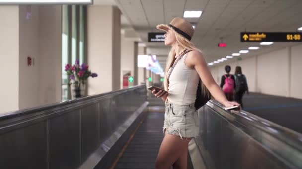 Jovem viajante com chapéu de palha em pé lateralmente na passarela do aeroporto — Vídeo de Stock