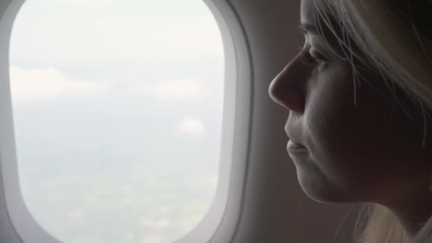 Reisende sitzt lächelnd am Fenster des Flugzeugs — Stockvideo