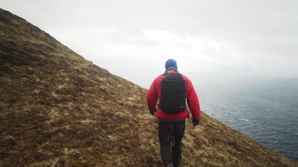 Vandrare promenader längs gräs sluttning till dimmiga havet — Stockvideo