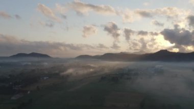 Bulutlu Gök, Siluetli Dağlar ve Kalın Sis Kaplayan Ovalar