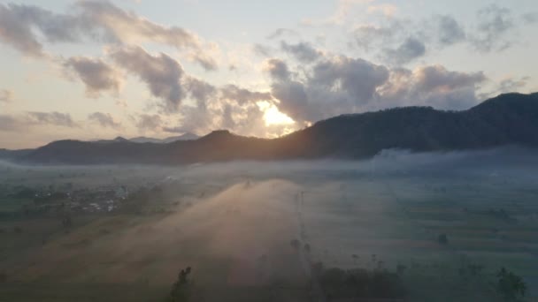 Alba dietro le silhouette delle montagne e i campi pianeggianti dietro la nebbia spessa — Video Stock