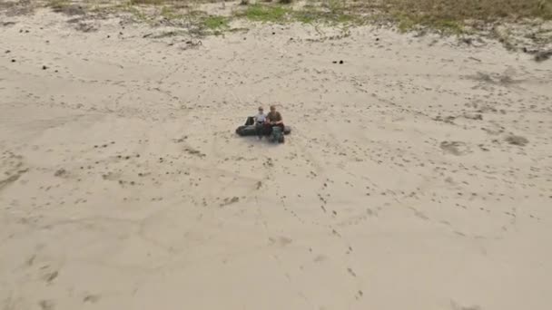 Paar sitzt in einem Baumstamm, als die Drohne davonfliegt und die schöne Küste enthüllt — Stockvideo