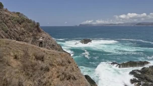 Orizzonte marino infinito e donna in cima alla scogliera con onde forti che si infrangono — Video Stock