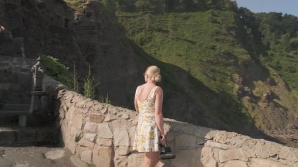 Blonde Tourist Admiring Picturesque View in Gaztelugatxe, Ισπανία σε μια ηλιόλουστη μέρα — Αρχείο Βίντεο