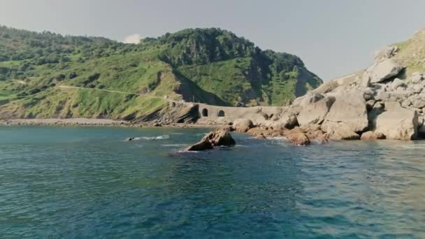 Wavy Waters Crashing Against Rocks and Gaztelugatxeko View in Background — 图库视频影像