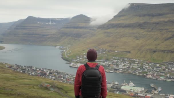 Vandrare står med staden nedanför och Mountain Ahead — Stockvideo