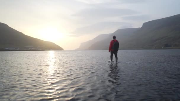 Homme marchant au lever du soleil dans le lac peu profond — Video