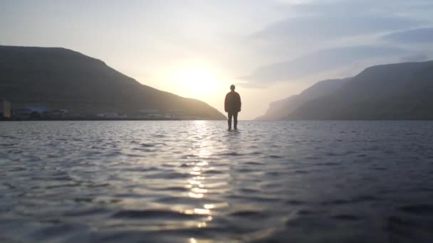Drönare av människan står vid soluppgången i den grunda sjön — Stockvideo