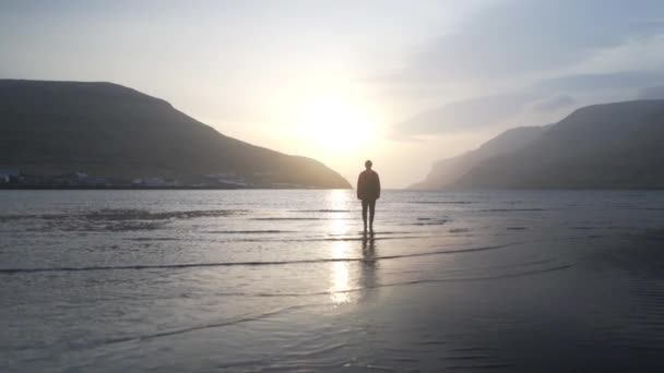 Дрони людини стоять на світанку в прибережному озері — стокове відео