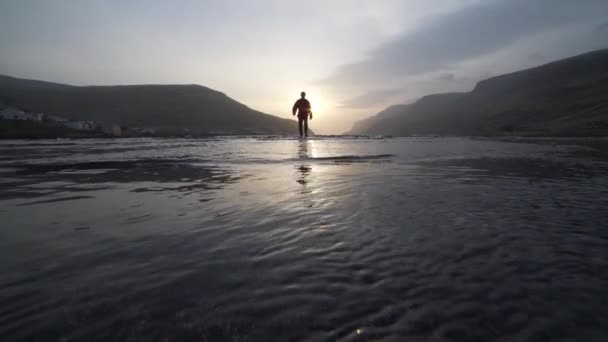 Homme marchant dans le lac peu profond au lever du soleil — Video