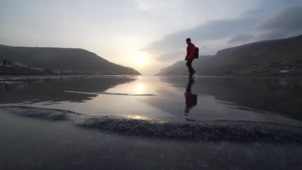 Homem caminhando ao nascer do sol através do lago raso — Vídeo de Stock
